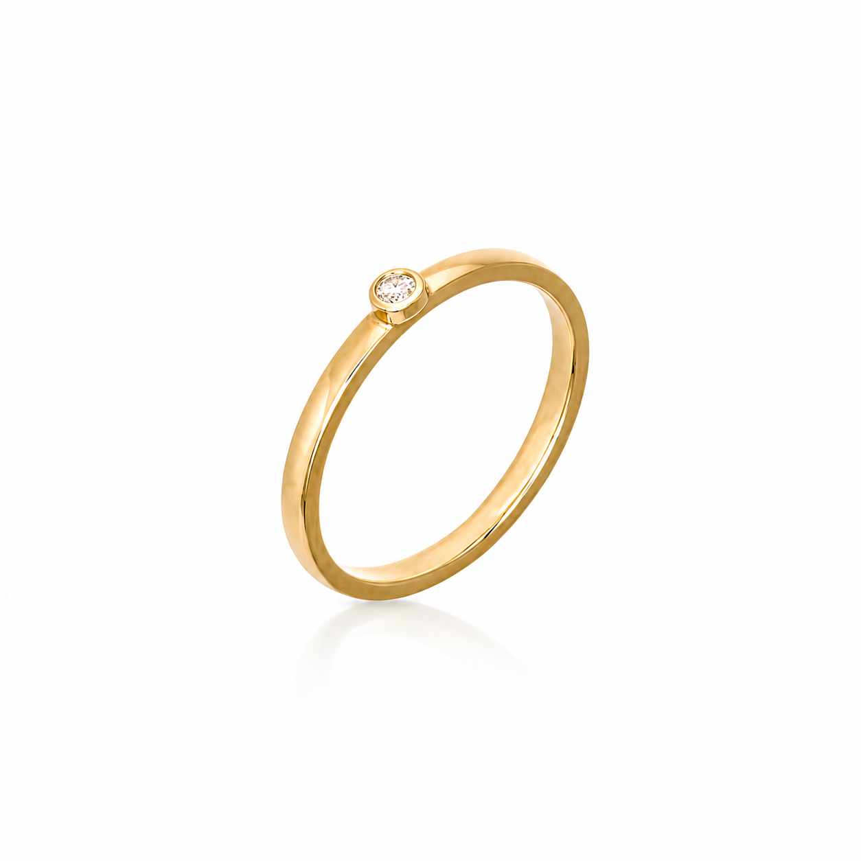 Minimalist 18K yellow gold ring with a single round bezel-set diamond on a slim polished band.