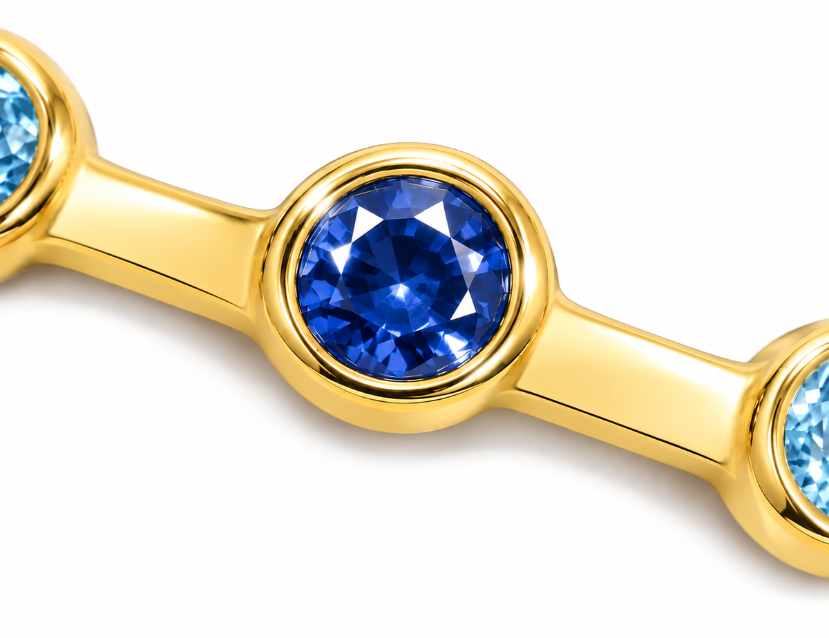Close-up of Azure Glint 18K gold ring showing light and dark blue sapphires in polished bezel settings