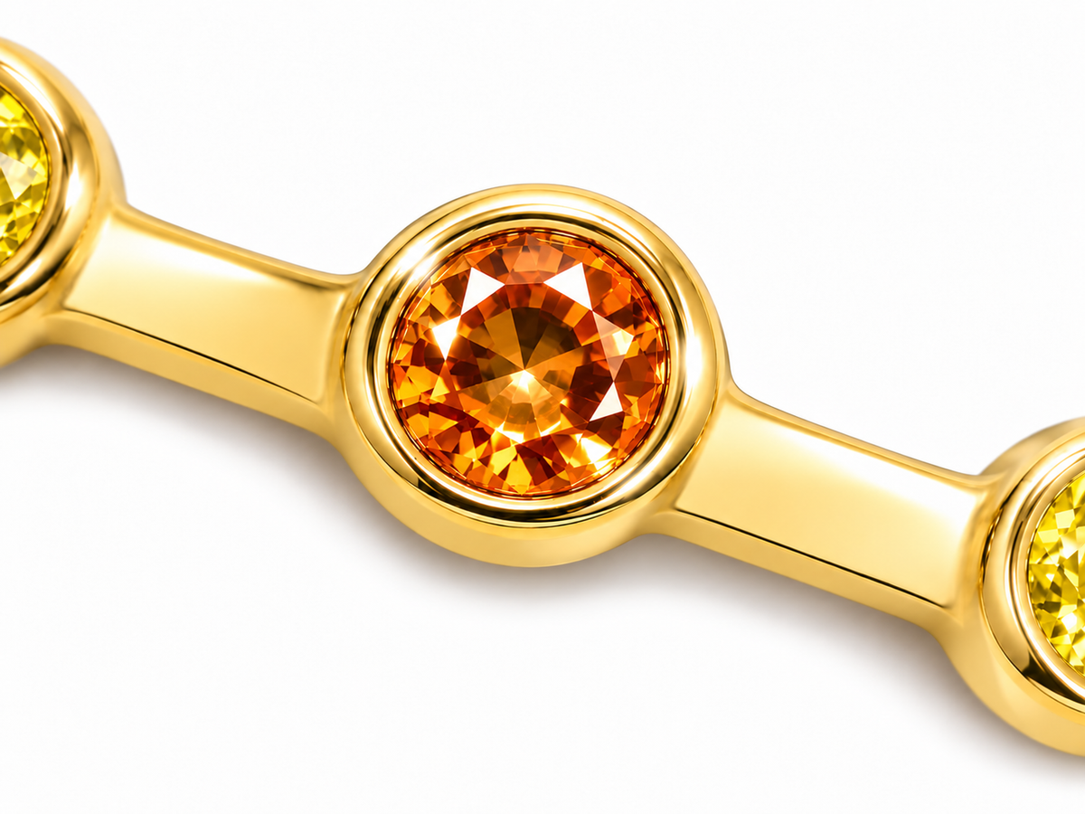 Close-up of round-cut orange and yellow sapphire bezel setting on Sunburst Glint 18K Gold Ring by Bed of Stones Jewelry
