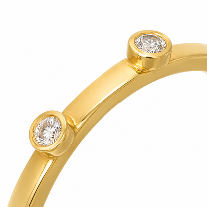 Close-up of round-cut white diamond bezel setting on Twin Dot 18K Gold Ring by Bed of Stones Jewelry