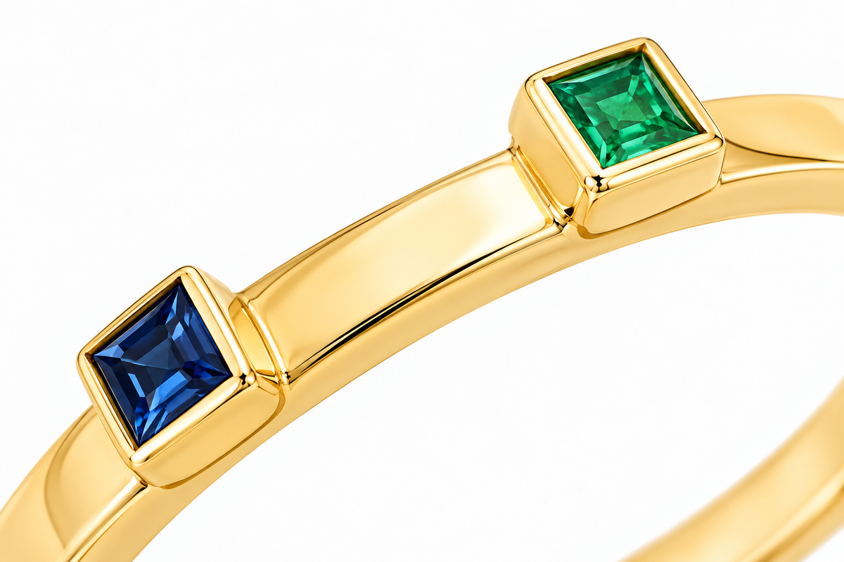 Close-up of princess-cut emerald and blue sapphire bezel setting on Twin Squares 18K Gold Ring by Bed of Stones Jewelry
